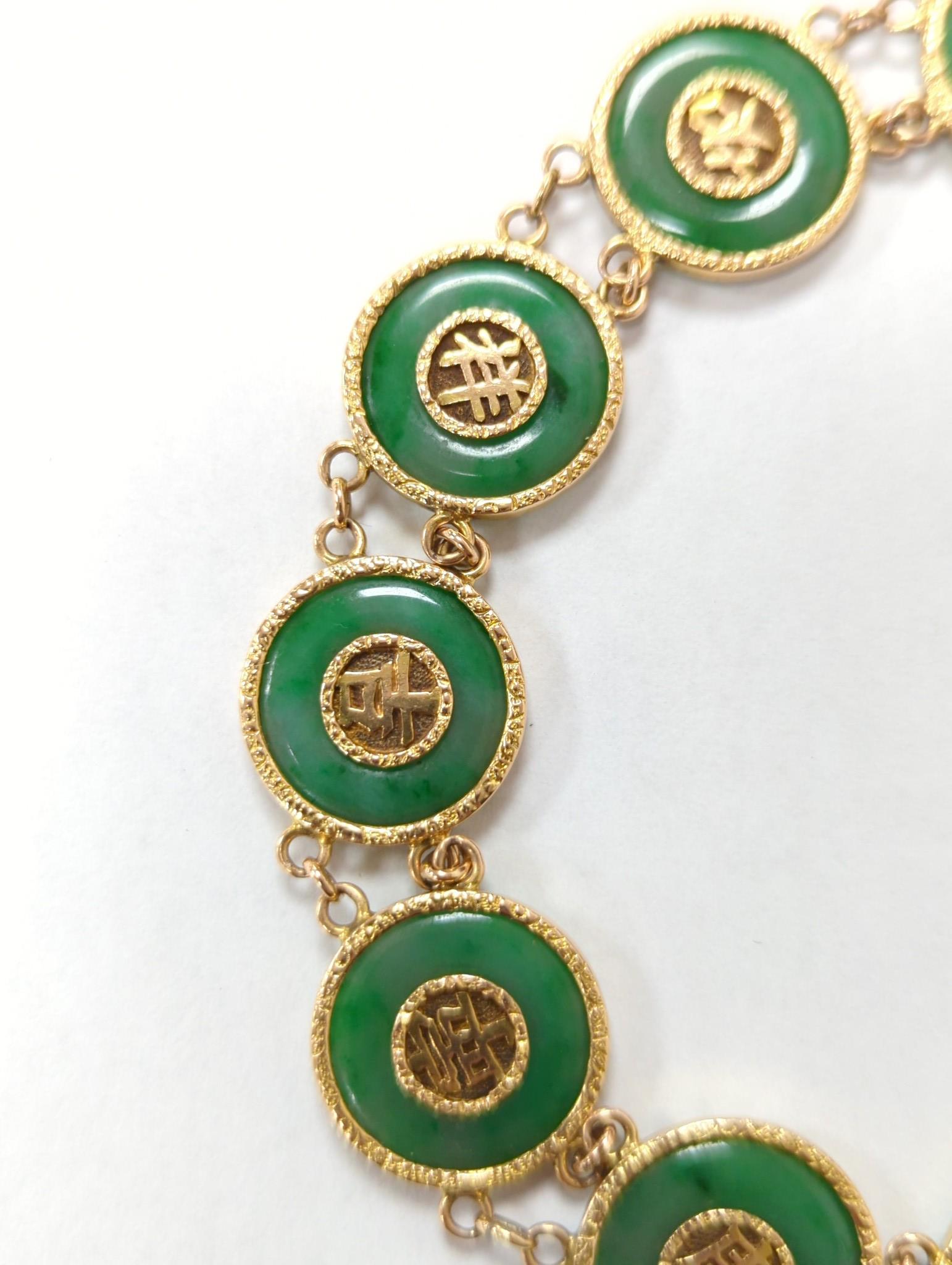 A Chinese yellow metal (stamped 18) and pierced eight stone jade disc set bracelet, with central Chinese characters, 16.5cm approx. gross weight 27.7 grams.